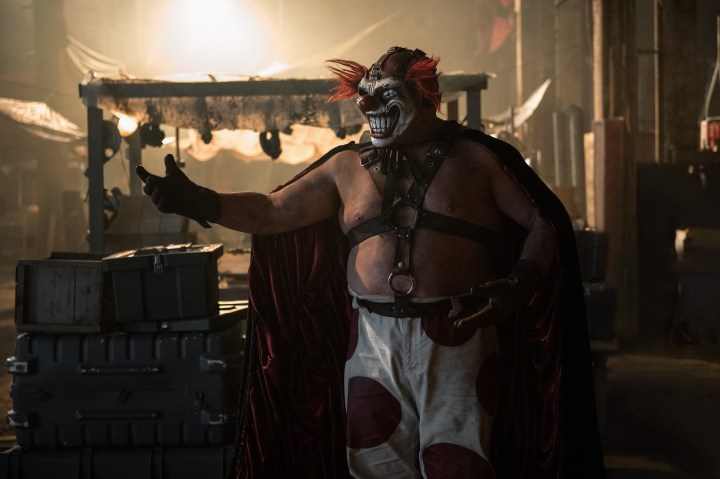 A vicious clown stands and readies for an attack.